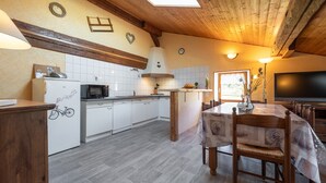 Una cocina con armarios blancos, un microondas, una estufa y un comedor con mesa y sillas.