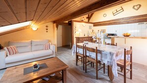 Un espacio habitable estilo loft, acogedor, con mesa de comedor, sofá y vigas de madera en el techo.
