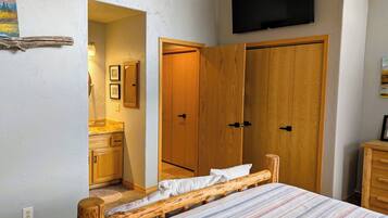 A bedroom with a bed, wooden wardrobe, a television, and a small bathroom.