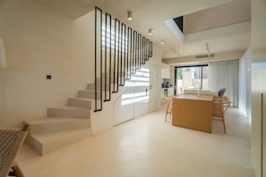 A modern interior with a staircase, a kitchen area, and a dining space.