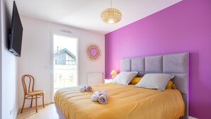 Een slaapkamer met een bed, een stoel, een televisie en een raam.