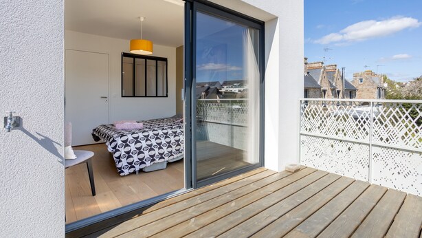 Een balkon met een bed, een stoel en een hanglamp.