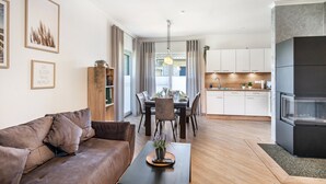 Una sala de estar moderna con sofá, mesa de comedor y zona de cocina.