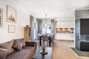 Ein modernes Wohnzimmer mit Sofa, Esstisch und Küchenbereich.