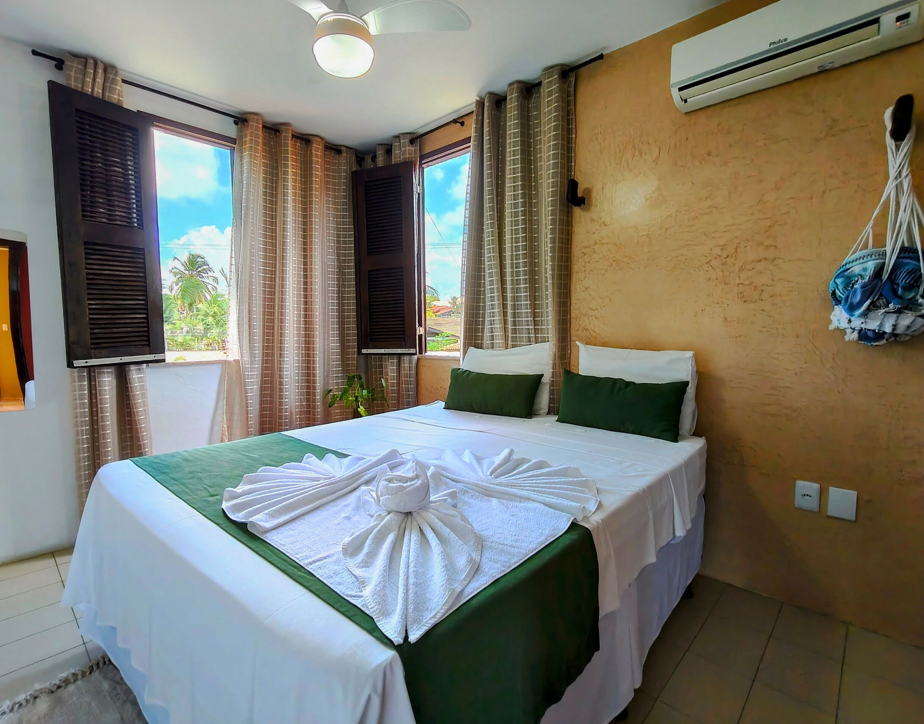 Habitación de hotel con cama, aire acondicionado, cortinas y vistas a zonas verdes.
