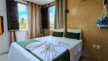 Habitación de hotel con cama, aire acondicionado, cortinas y vistas a zonas verdes.