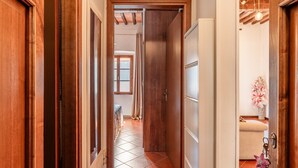 A hallway with wooden doors, a tiled floor, and a window with curtains. - Casa Ilaria Vicopisano (Vicopisano)