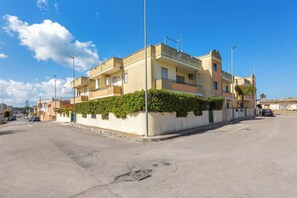 Un immeuble résidentiel à plusieurs étages, doté de balcons, d’un toit plat et situé le long d’une rue pavée.