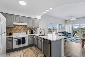 A modern kitchen with grey cabinets, a white stove, and a dishwasher. - Madeira Beach Escape  Pool + Water Views (Madeira Beach)
