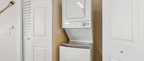 A laundry room with a washer and dryer, a door with a window, and a wall-mounted thermostat.