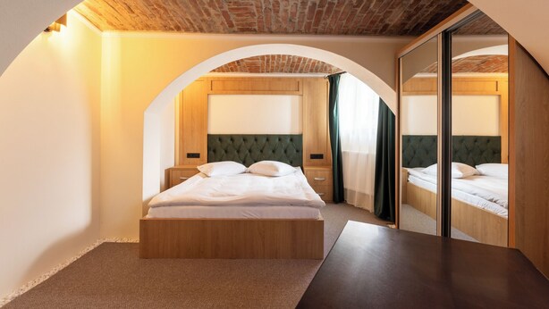 A bedroom with a wooden bed, a mirror, and a brick ceiling. - The Vault Apartment | Unique Stay | Sibiu Center (Sibiu)