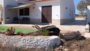 Una casa de dos pisos con un patio, mobiliario exterior y un jardín.