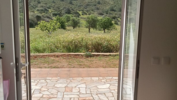 Una habitación con vistas a un paisaje montañoso, un letrero que indica una salida y un patio con suelo de piedra.