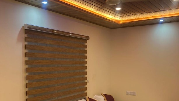 Ein Hotelzimmer mit zwei Betten, Holzkopfteilen, einem Deckenventilator und einem Fenster mit Jalousien.
