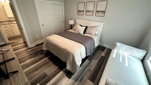 A bedroom with a bed, bedside table, lamp, and artwork on the wall. - Chic Westerville Retreat Near Uptown Westerville • Walk to Coffee • Sleeps 6 (Westerville)
