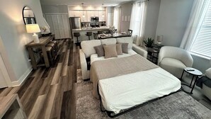 A modern hotel room with a large bed, a sofa, a dining table, and a kitchen area. - Chic Westerville Retreat Near Uptown Westerville • Walk to Coffee • Sleeps 6 (Westerville)