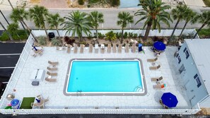 Ein Luftbild eines Dachpools mit Liegestühlen und Palmen.