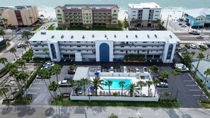Ein mehrstöckiges Hotel mit Innenhof, Schwimmbad und Blick auf den Strand.