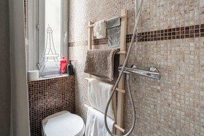 Ein Badezimmer mit Toilette, Dusche und einem Fenster mit Blick auf einen Turm.