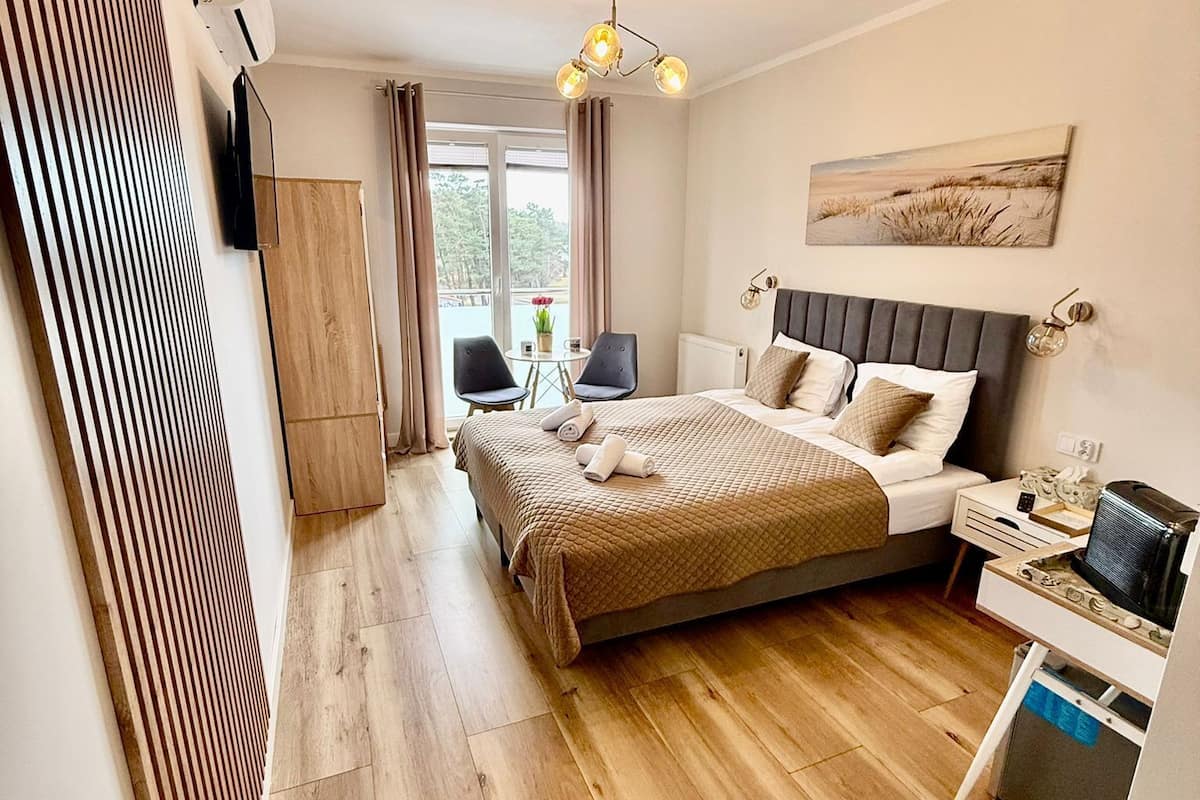 Een hotelkamer met een bed, nachtkastje, televisie en uitzicht op de omgeving.