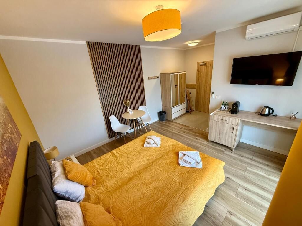 A modern hotel room with a bed, a TV, a desk, and a wardrobe.