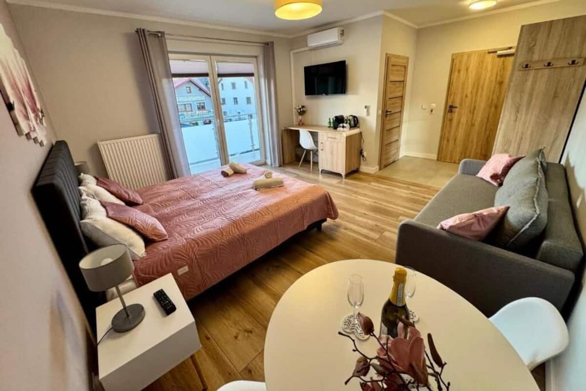 Een hotelkamer met een bed, bureau, televisie, bank en balkon met uitzicht.