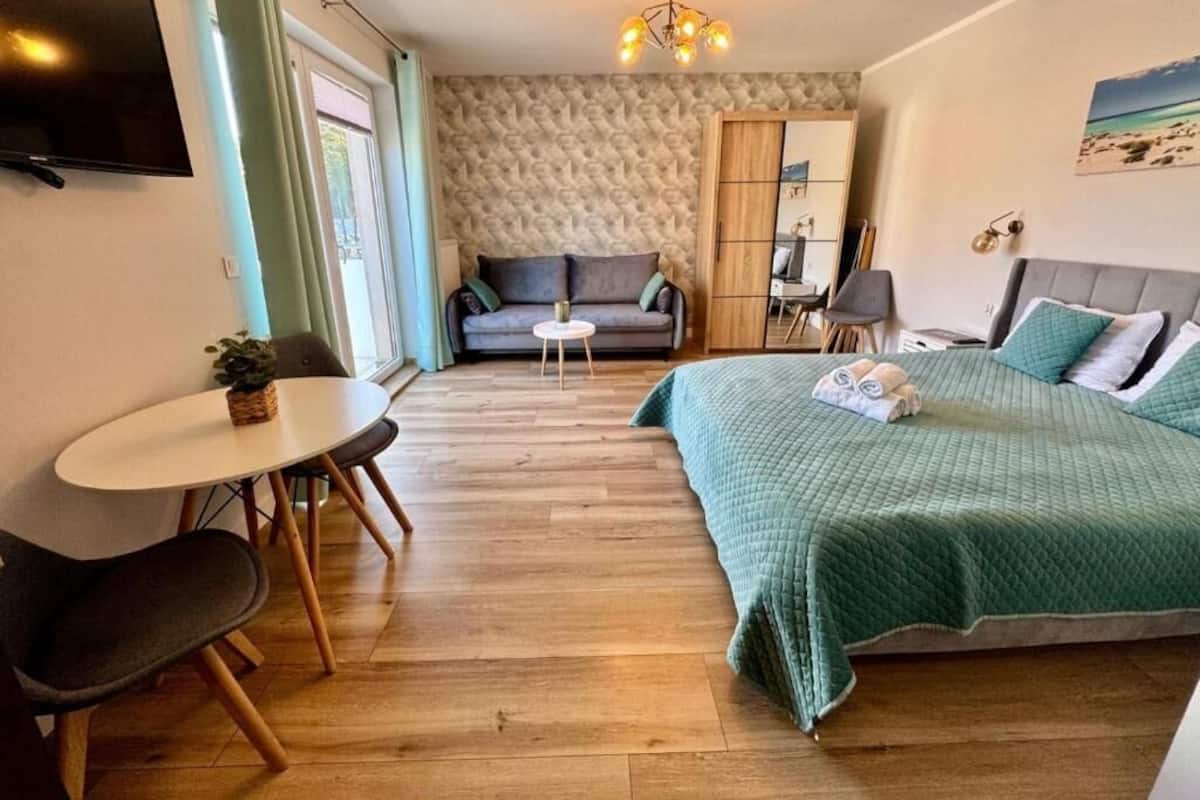 Een kamer met een bed, een slaapbank, een tafeltje en een televisie.