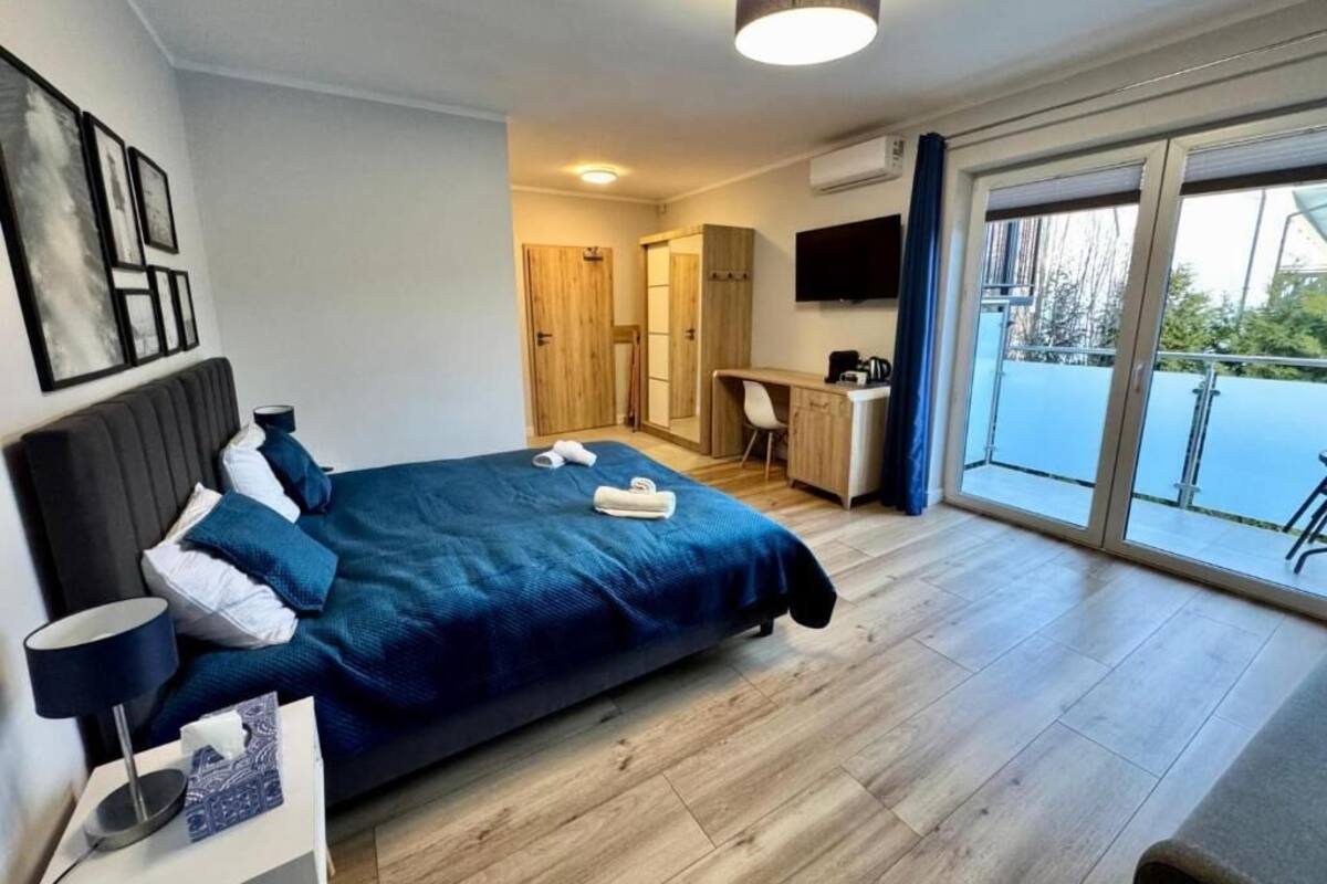 Een moderne hotelkamer met een bed, nachtkastje, bureau en uitzicht op het omliggende landschap.