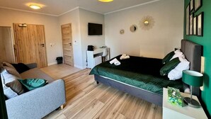 A bedroom with a bed, a desk, a chair, and a TV. - Pokoje Balticus Mrzeżyno (Mrzeżyno)