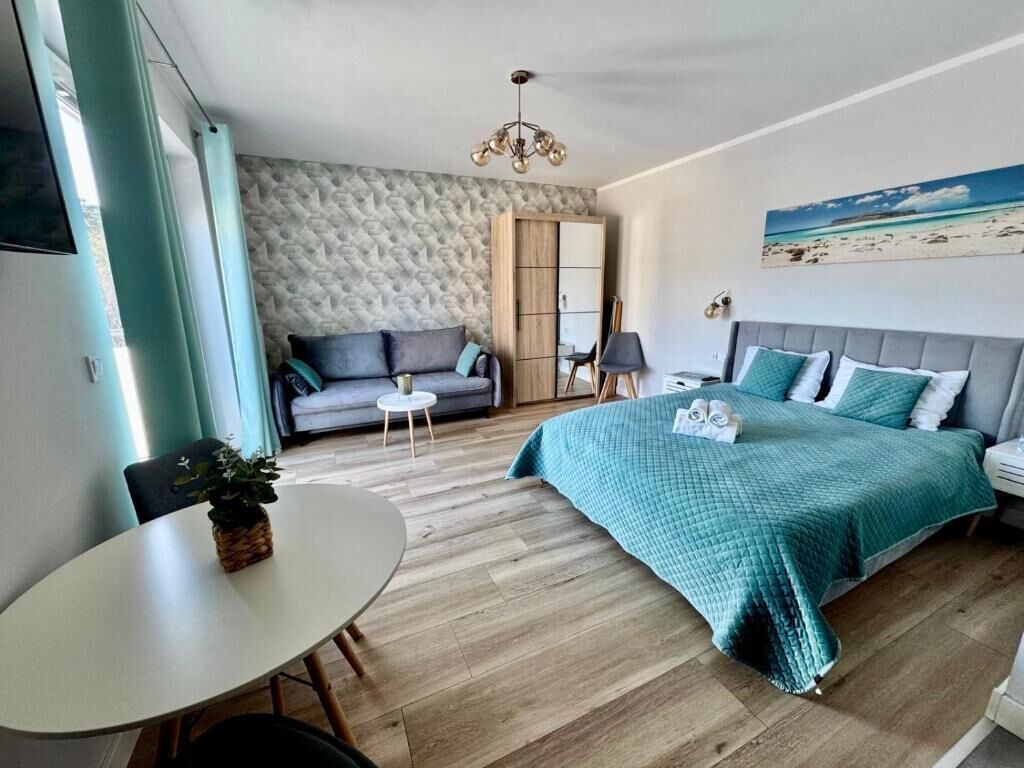 A bedroom with a bed, a sofa, a dining table, and a chair.