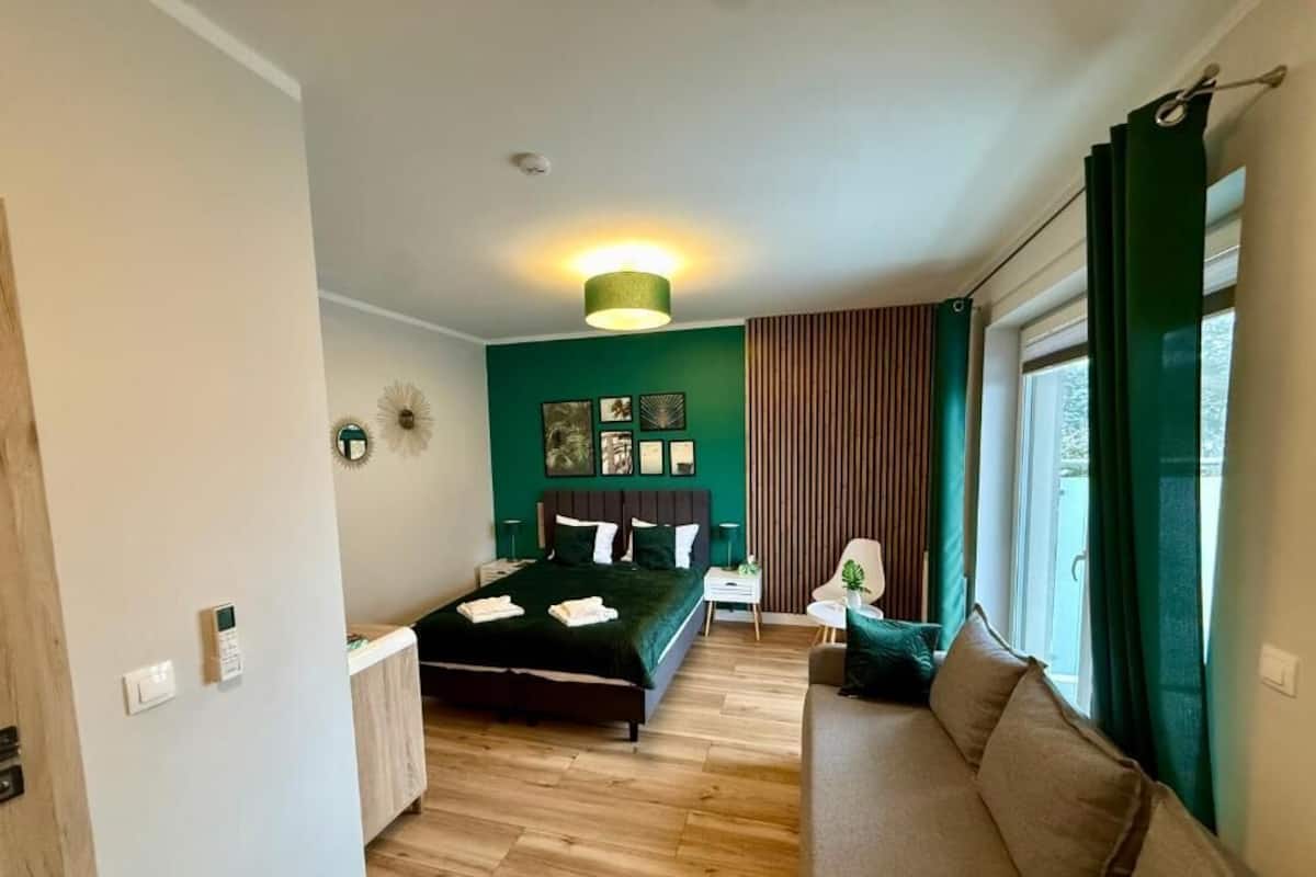 Een slaapkamer met een bed, een bank, een bureau en een raam met gordijnen.