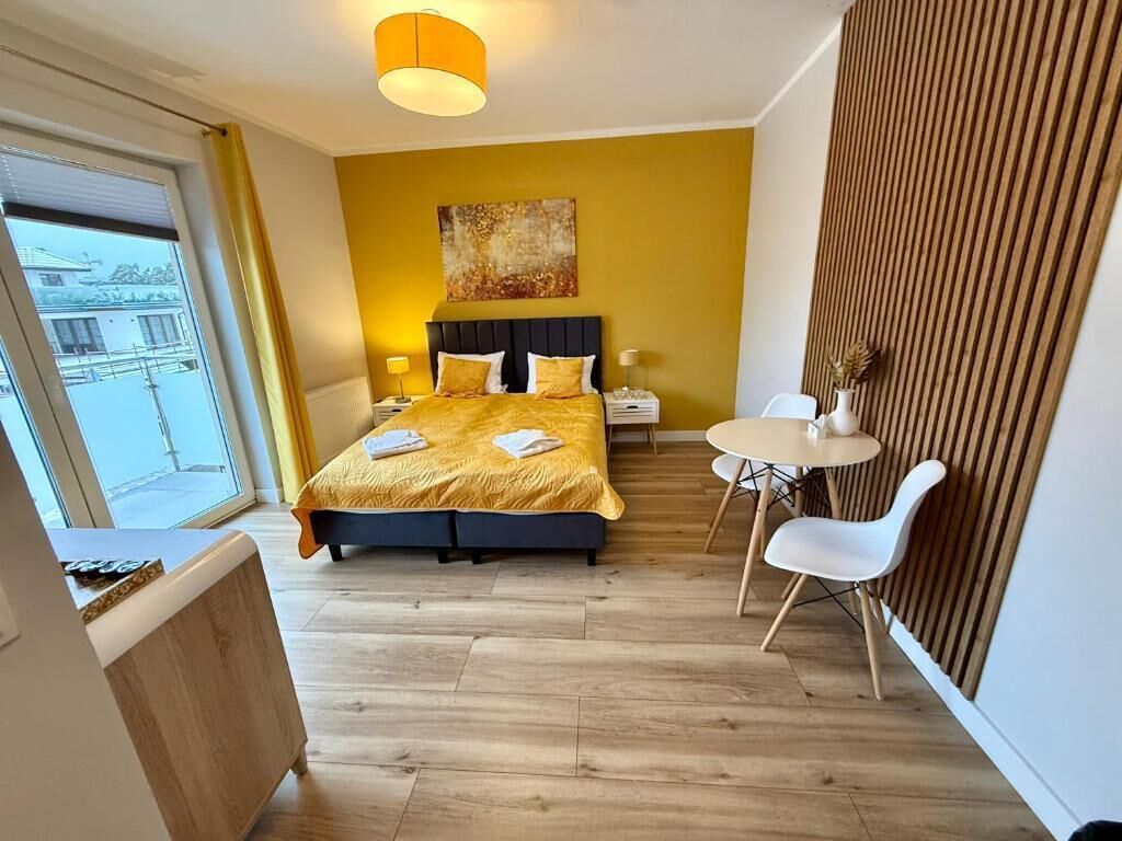 Una camera d'albergo moderna con un letto, un comodino, una lampada e un piccolo tavolo rotondo con sedie.