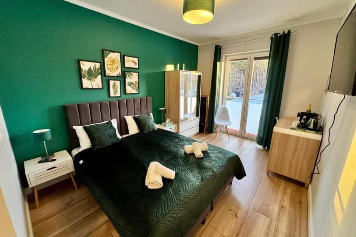 Een slaapkamer met een bed, nachtkastjes, een kledingkast en een bureau met een stoel.