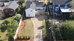 Vista aérea de una zona residencial con una casa que tiene un porche delantero, un garaje y un patio con jardines.