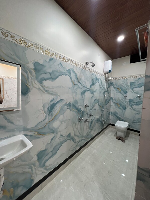 A bathroom with marble walls, a sink, a toilet, and a shower. - JALANGI EMPIRE (Mayapur)