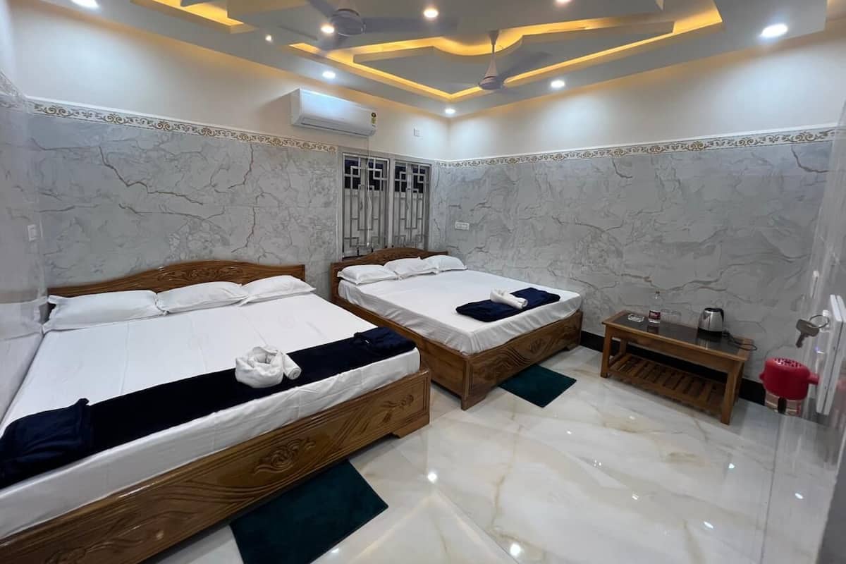 A hotel room with two wooden beds, marble walls, a small wooden table, and a ceiling with recessed lighting.