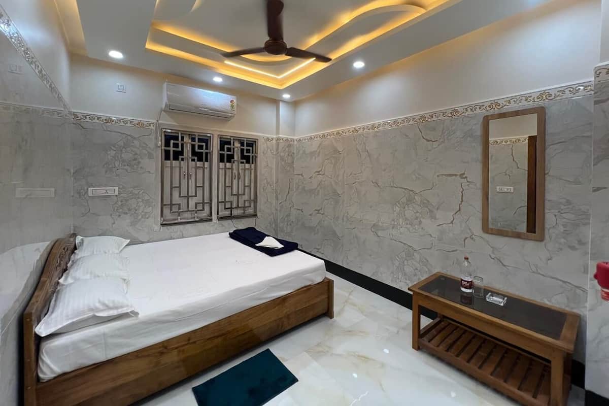 A bedroom with a bed, a bedside table, a mirror, and a ceiling fan.