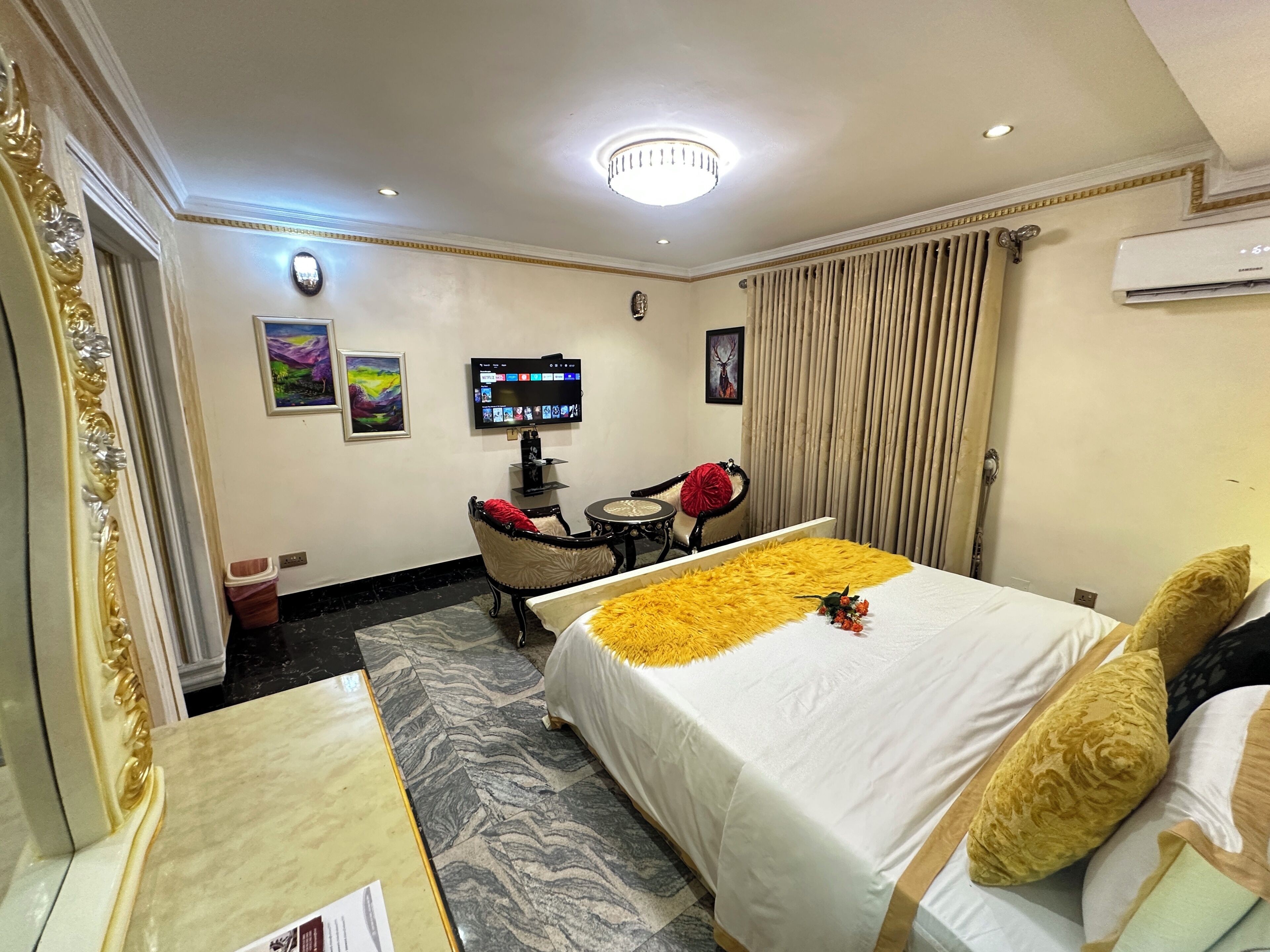 A hotel room with a bed, a desk with a chair, a television, and a window with curtains.