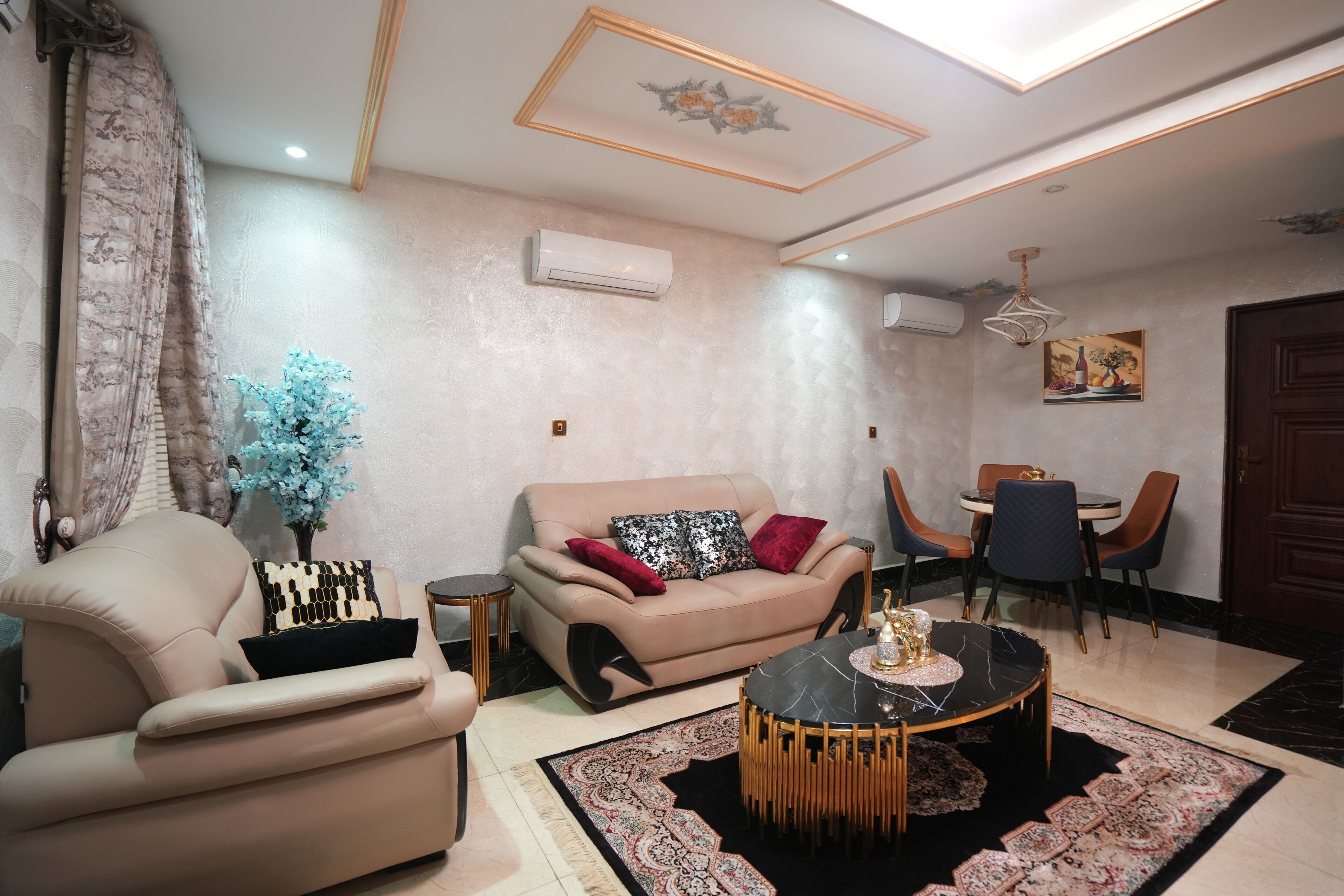 A living room with a beige sofa, a round coffee table, and a dining area with chairs and a table.
