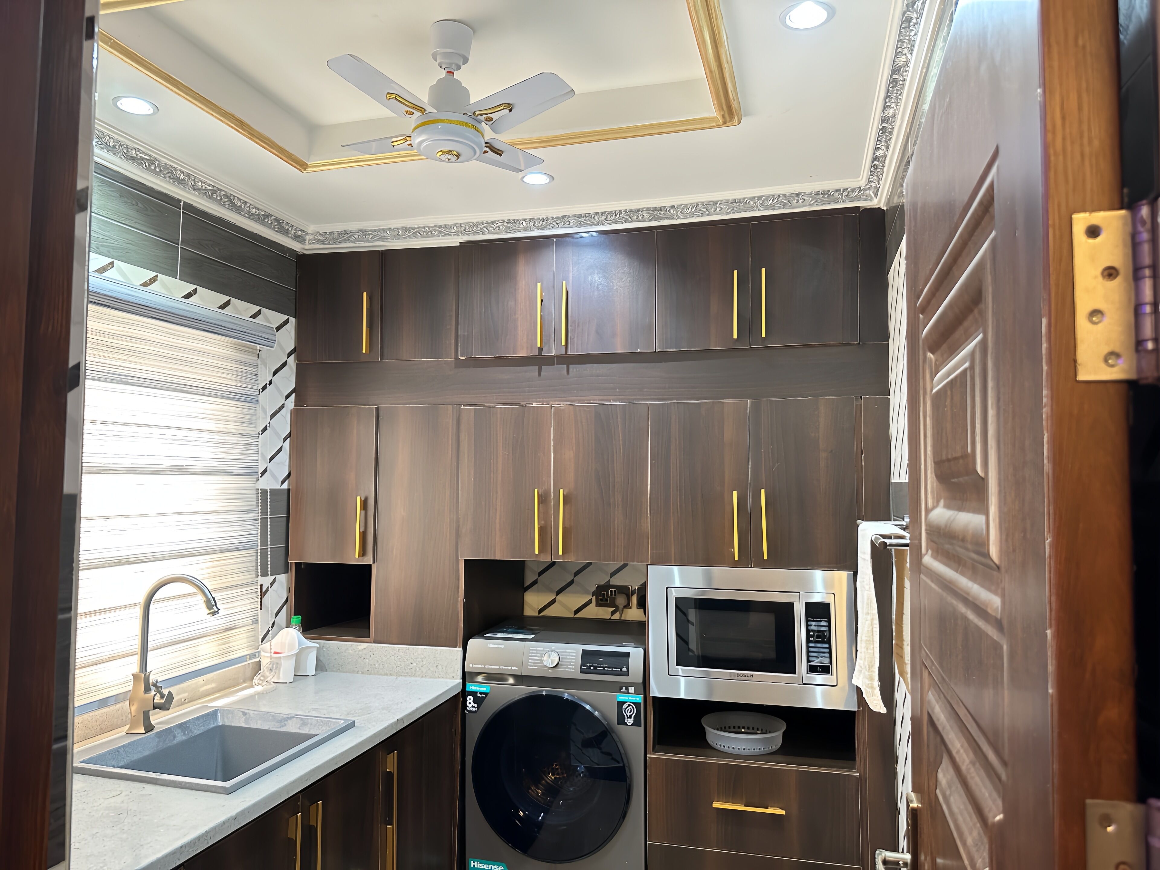 Una cocina compacta equipada con lavadora, microondas y pileta.