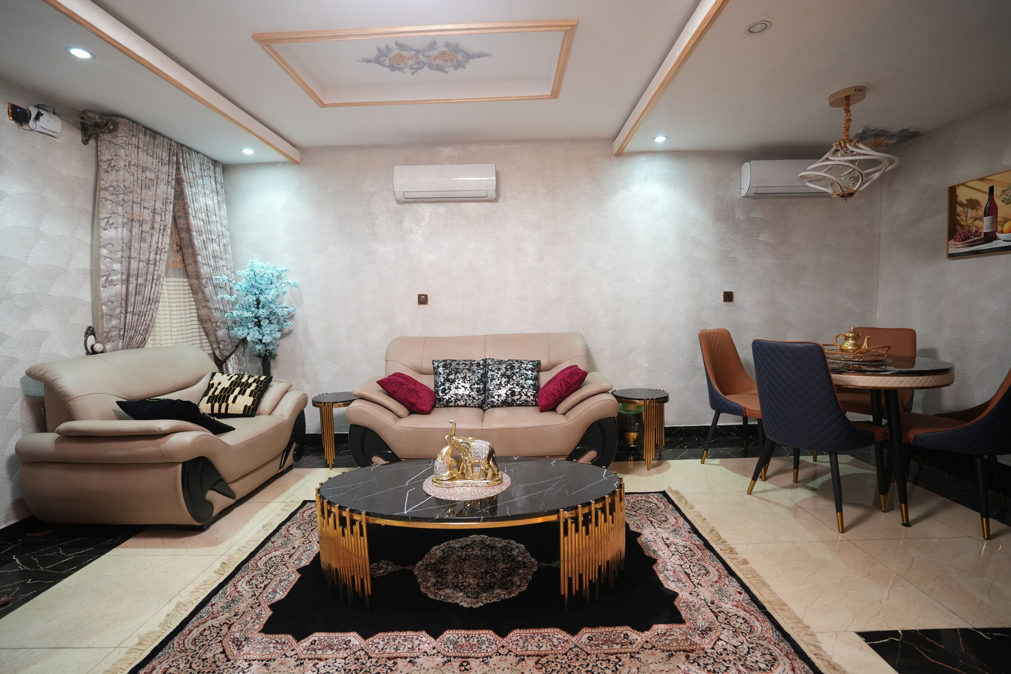 A modern living room with a sofa, a round coffee table, and a dining area with chairs and a table.