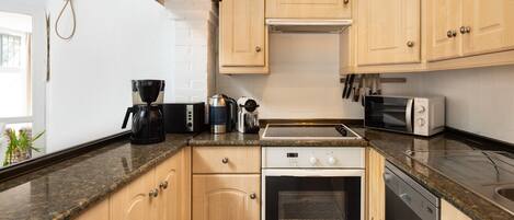 A modern kitchen with wooden cabinets, a Bosch oven, a coffee maker, and a toaster.
