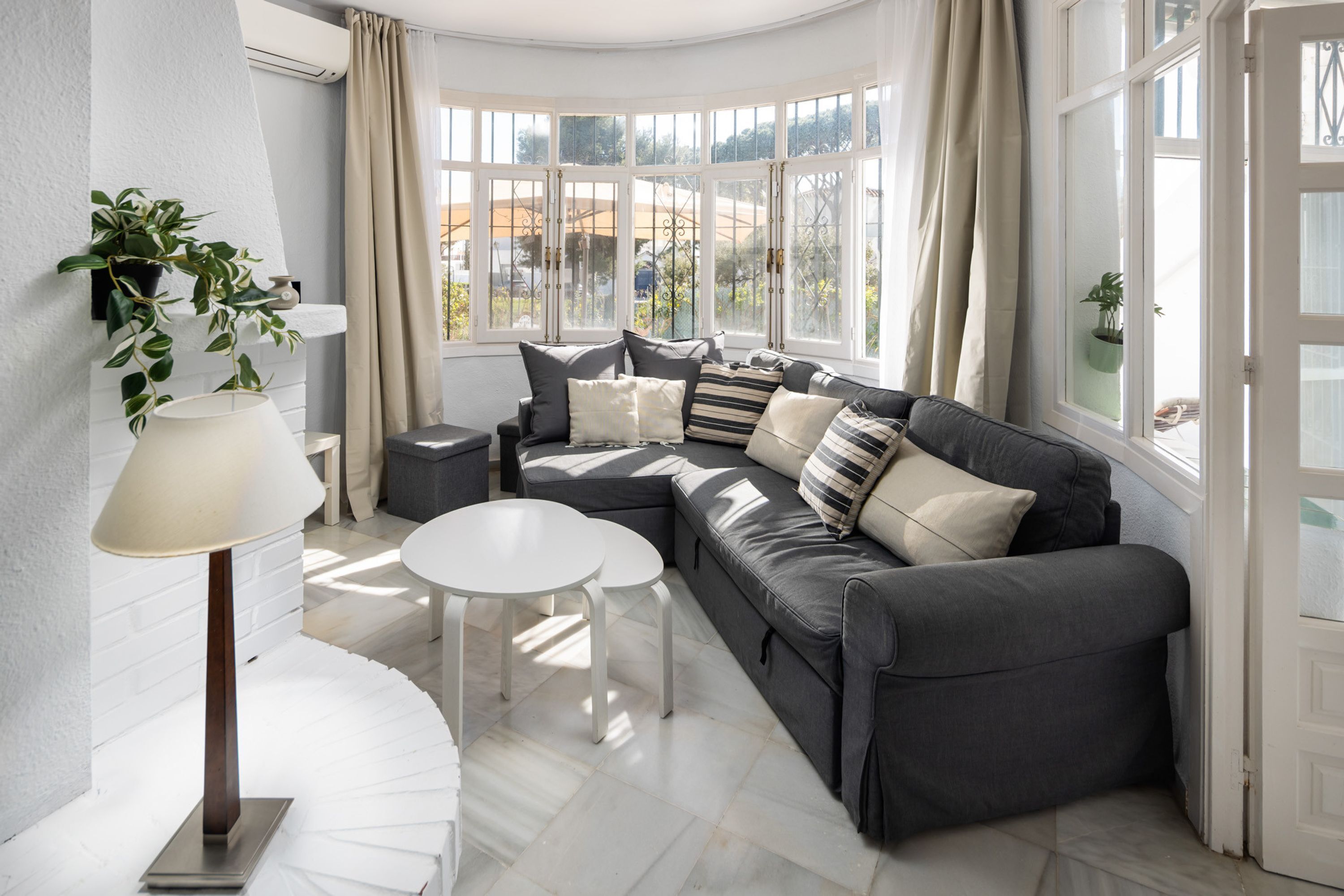 A modern living room with a grey sofa, a white table, and a floor lamp.