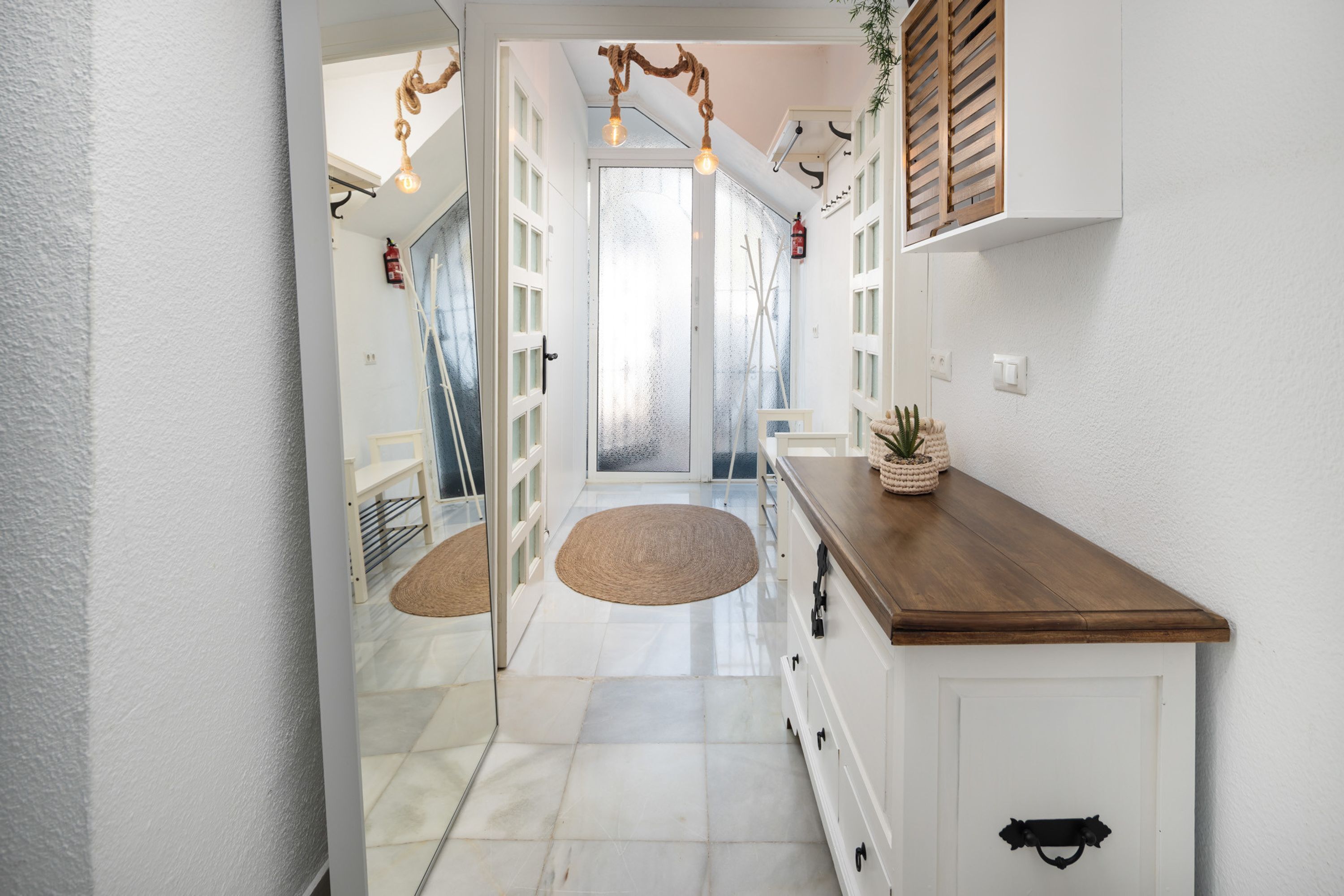 A hallway with a wooden counter, a white cabinet, and a mirror reflecting the space.