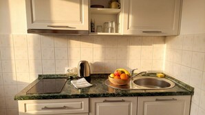 A kitchen with white cabinets, a marble countertop, a kettle, a bowl of fruit, and a sink. - One-bedroom apartment Casa Vidasca 103 with the pool and the private balcony (Novalja)