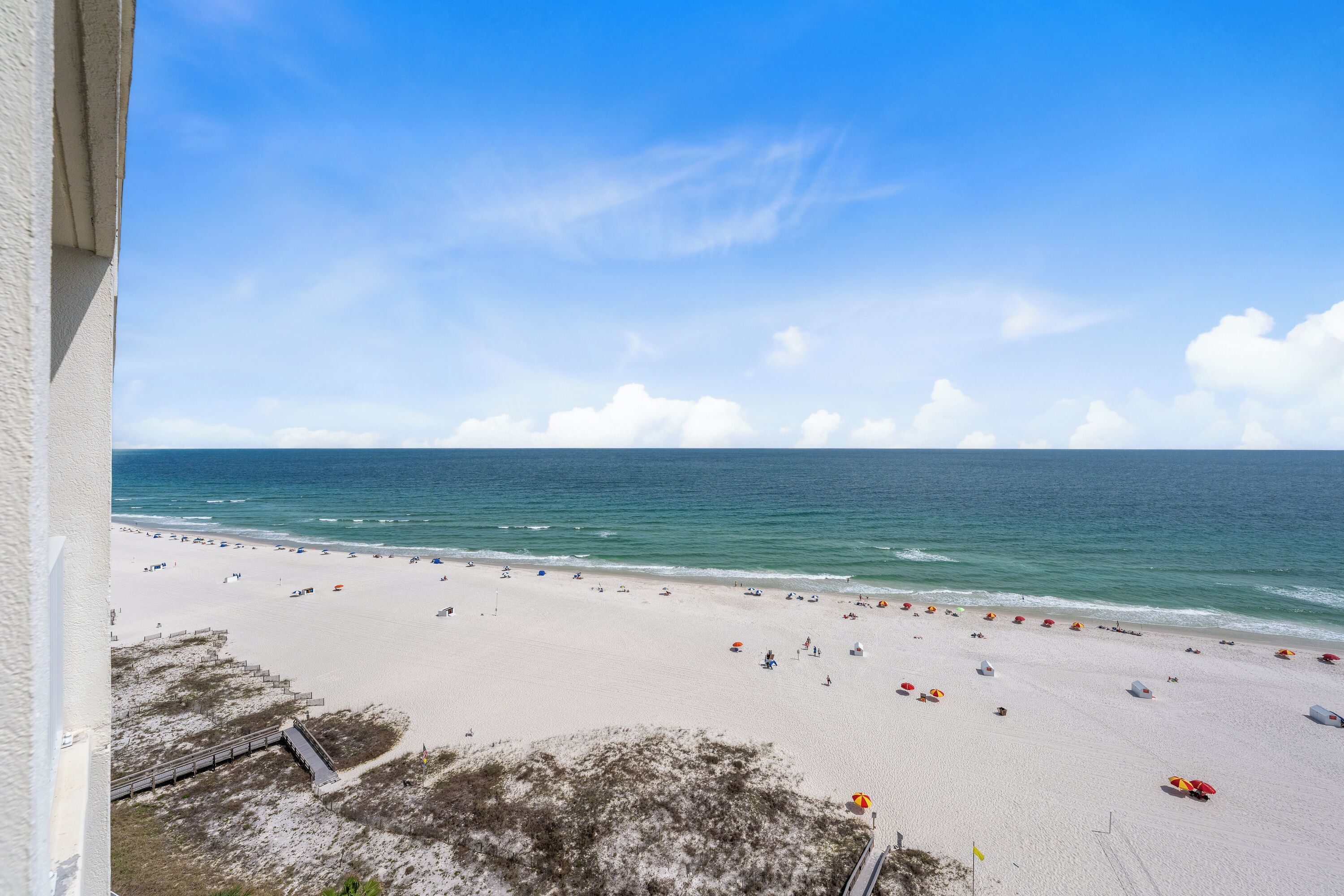 A beach with a clear sky, a sandy shore, and a few umbrellas.