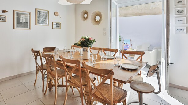 Un comedor con sillas de madera, una mesa preparada para cuatro personas y un amplio ventanal con vistas.