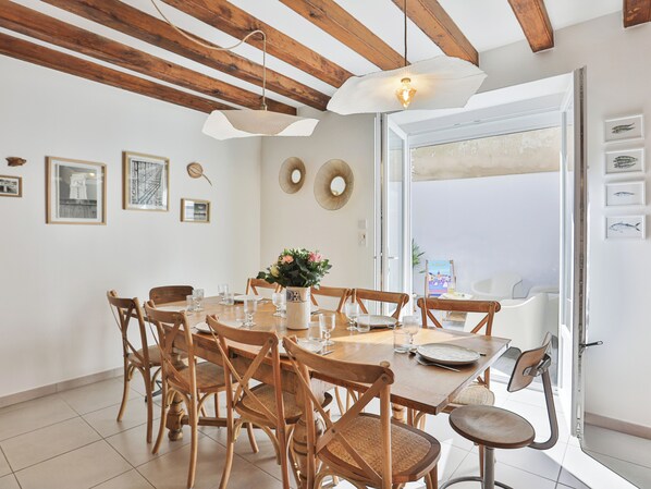 A dining area with wooden chairs, a table set for four, and a large window with a view.