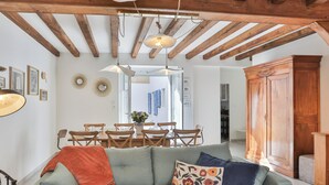Una sala de estar acogedora con sofá, vigas de madera, comedor y un armario.