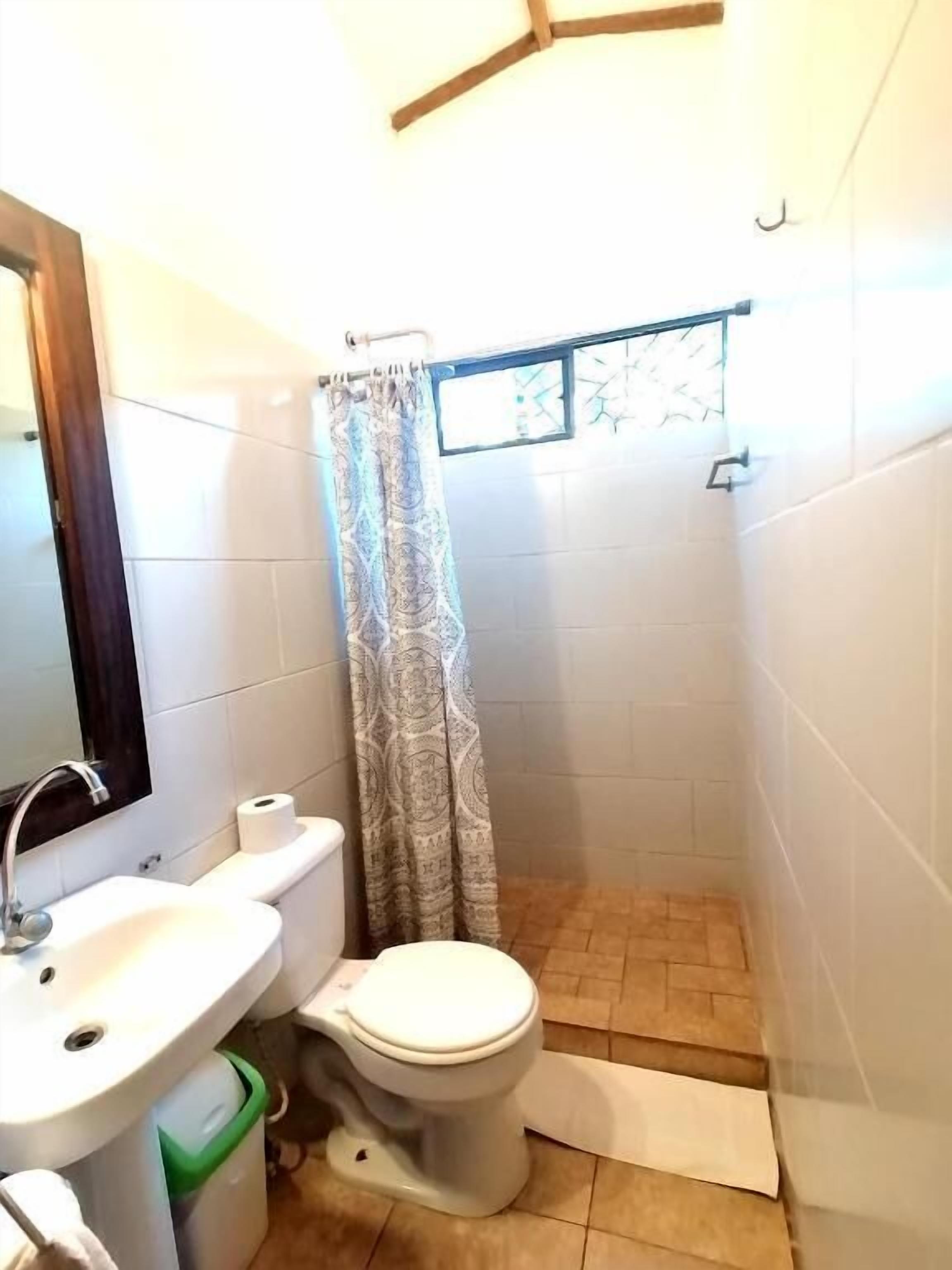Une petite salle de bain avec des toilettes, un lavabo et un rideau de douche.